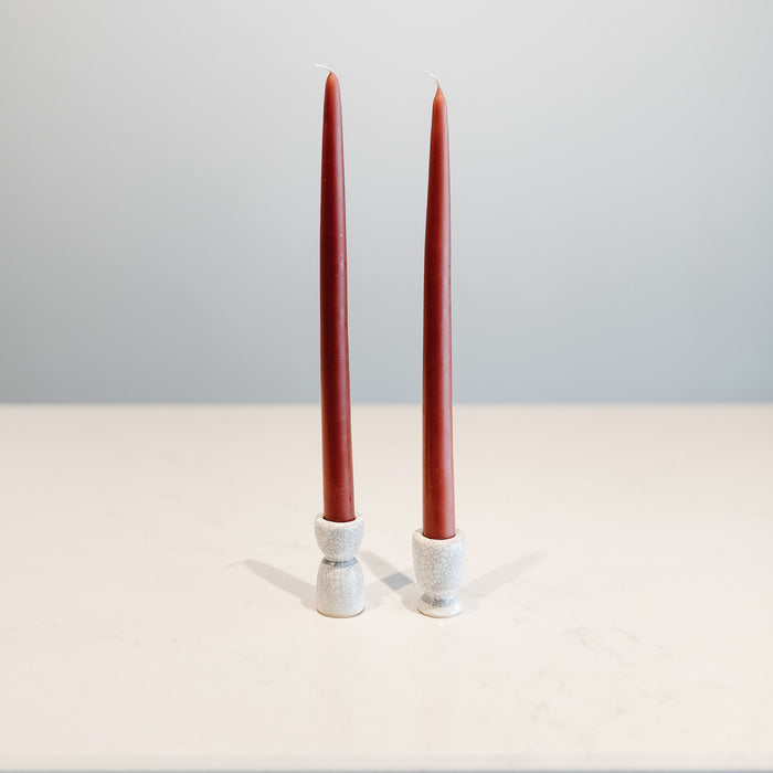Small and large candleholders with tapered candles, side by side, difference of one inchin size.